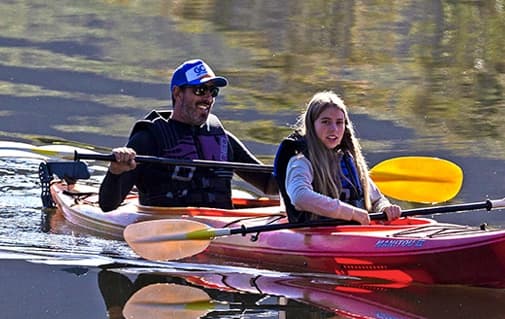 Two paddlers sharing a quiet stretch of river in kayaks