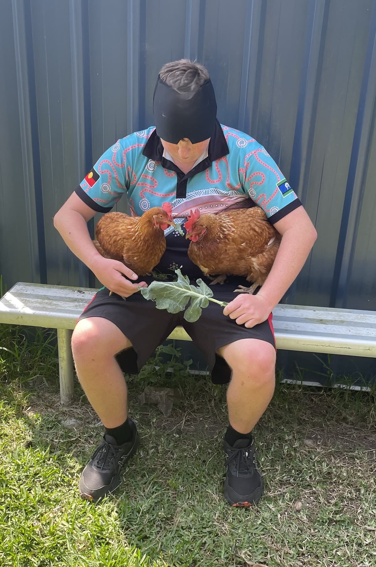 A student sitting quietly with two chickens on their lap