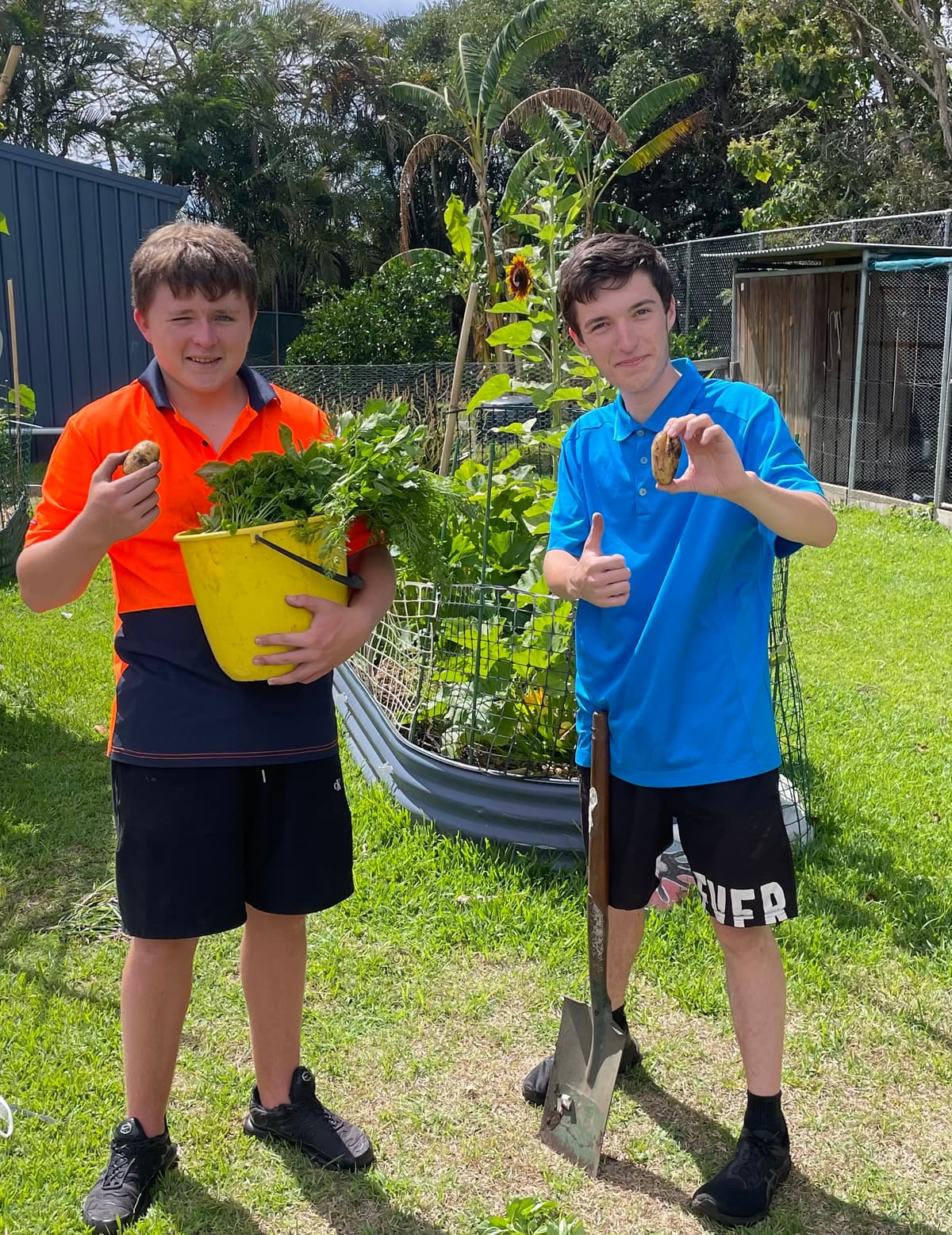 Two students holding a pot of seedlings they have just planted